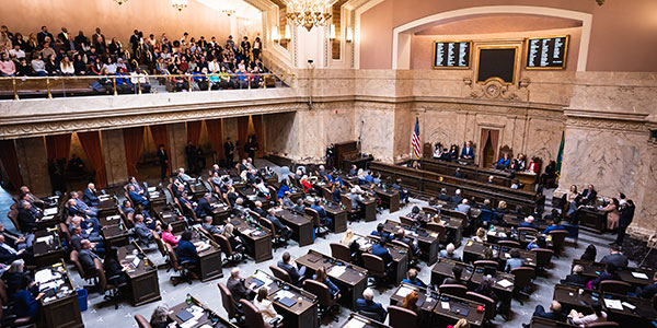 An above and wide-angle shot of Washington state legislators seated in the house chambers as Gov. Jay Inslee delivers the State of the State address. 