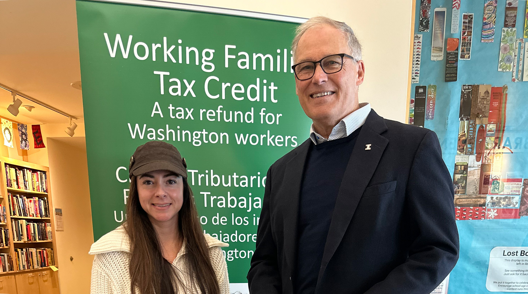 Two people stands in front of a sign displaying "Working Family Tax Credit," representing financial support for families.